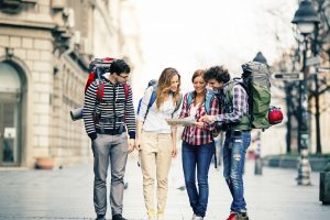 Cheerful backpackers looking map on the street in the city.