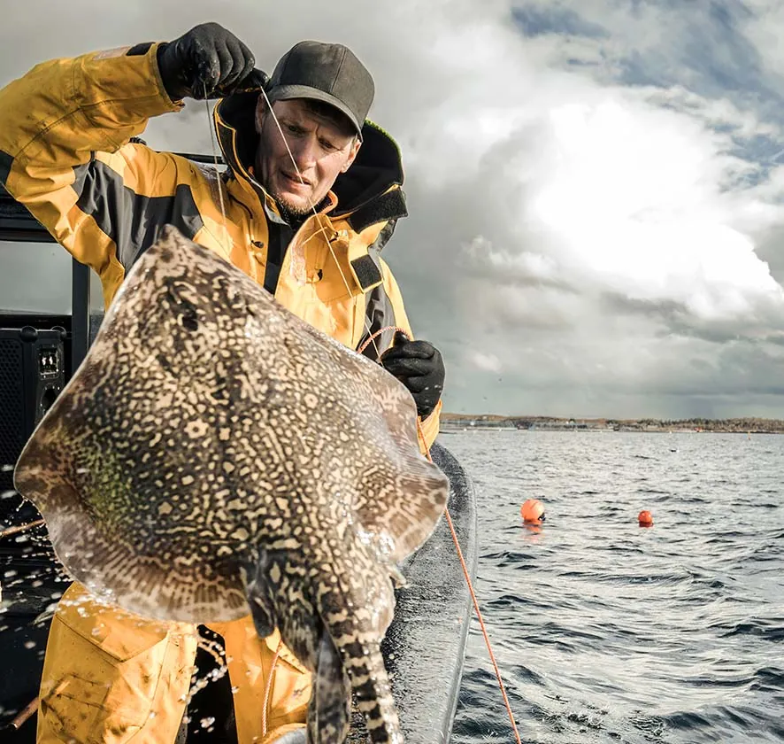 Man on a fishing boat holding a fish